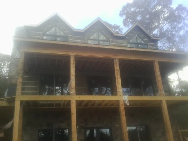 Dormers and porch framing on a large log home under construction — Roof Coating work by our crew in Wakita