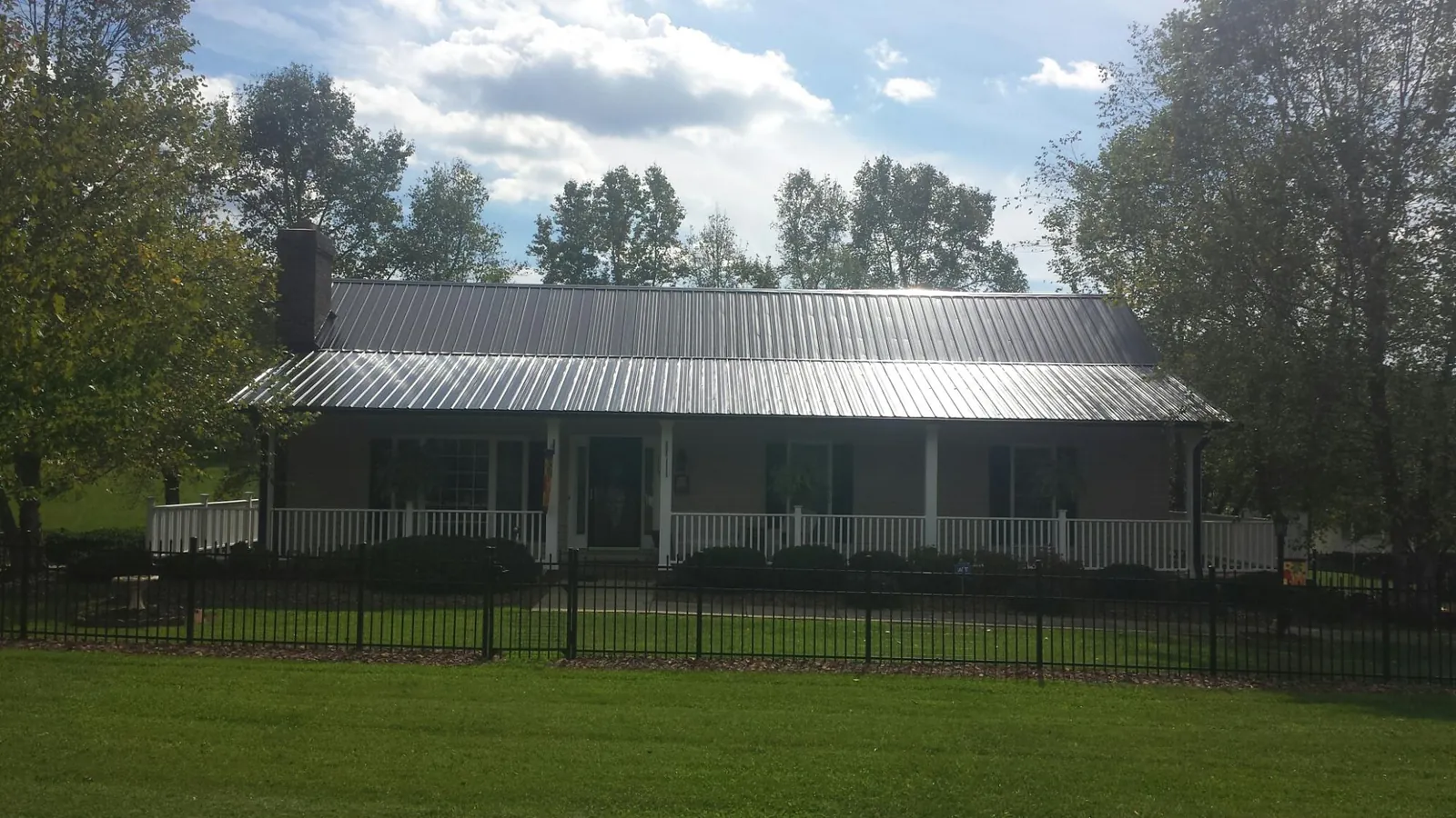 Gray metal roof on a brick ranch with a full width front porch — Gutter Guard Installation work by our crew in Wakita