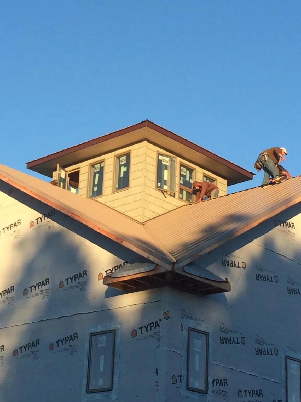 Roofers working around a rooftop cupola on a new metal roof at sunset — Roof Waterproofing in Wakita by Roofing Brothers